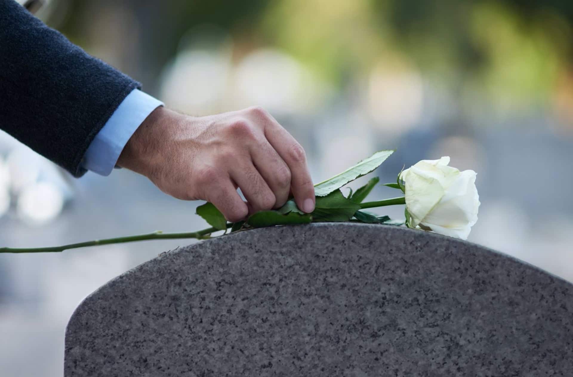 A Man Placing A White Rose On A Grave | Medicaid Planning in Washington | Legacy Law Group