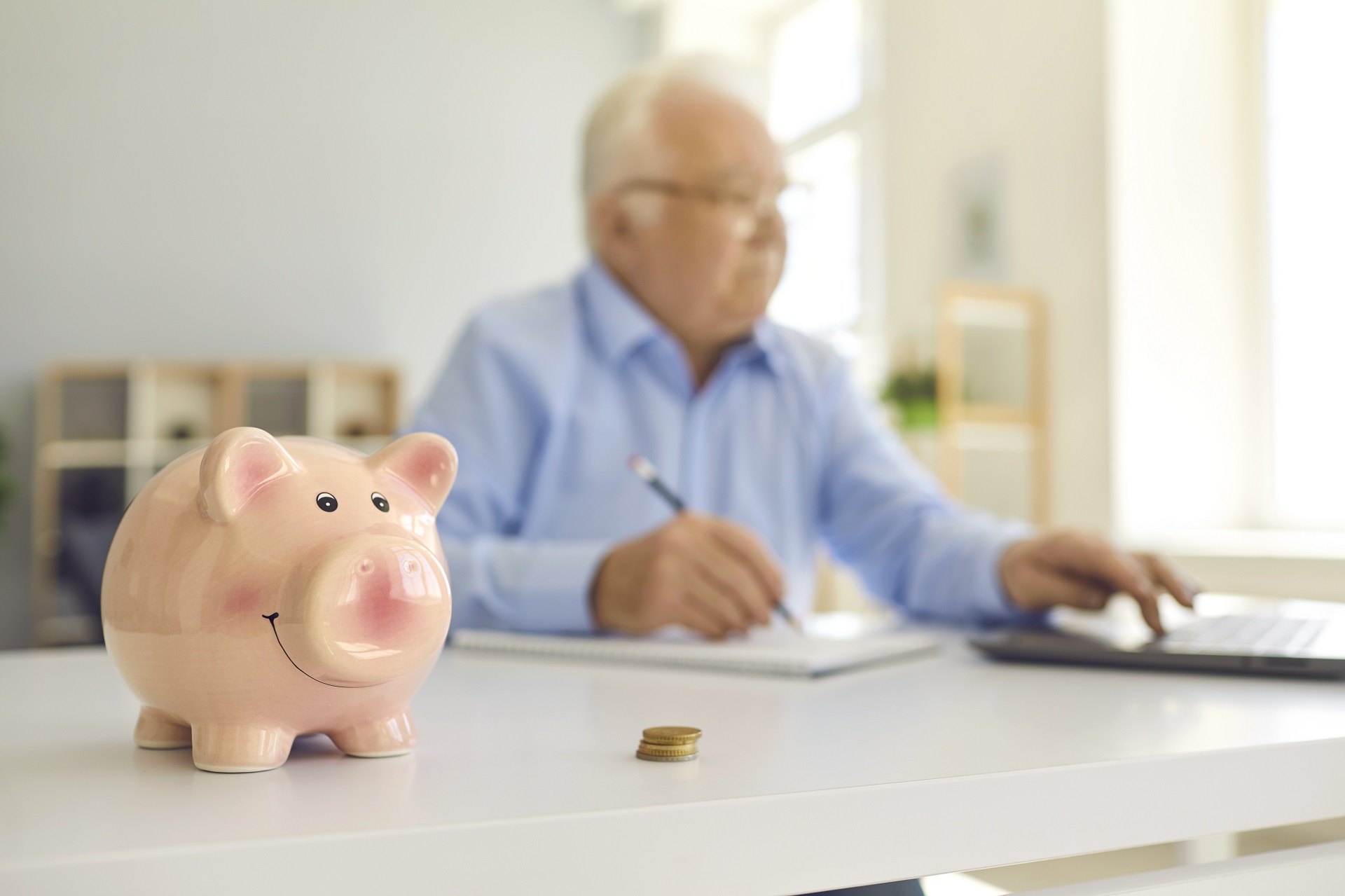 Piggy Bank On The Desk With Blurred Retired Man | Living Will vs Living Trust​ | Legacy Law Group