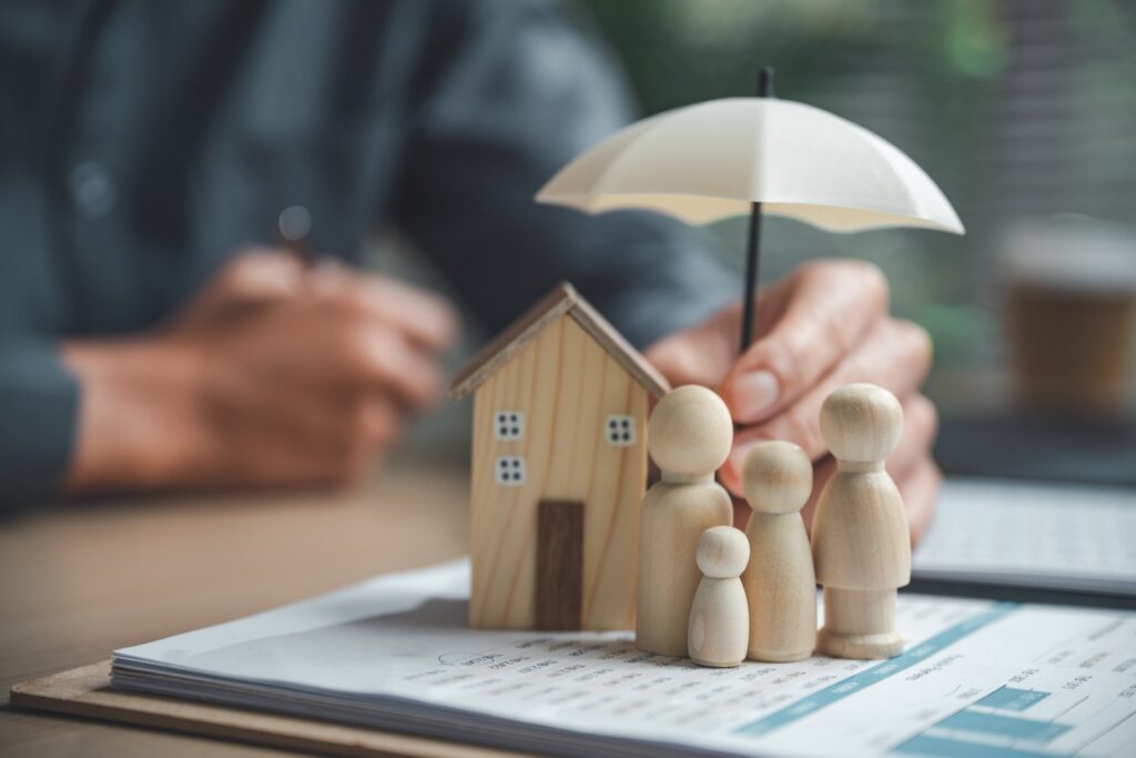 Small wooden home and wooden family on top of paperwork