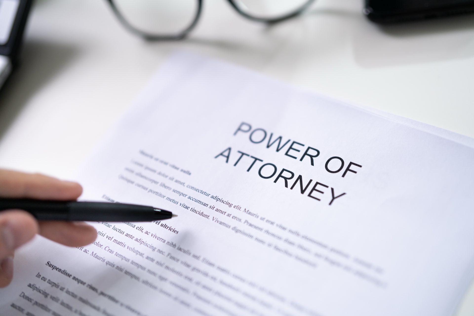 Zoomed in on a hand holding a pen filling out power of attorney paperwork